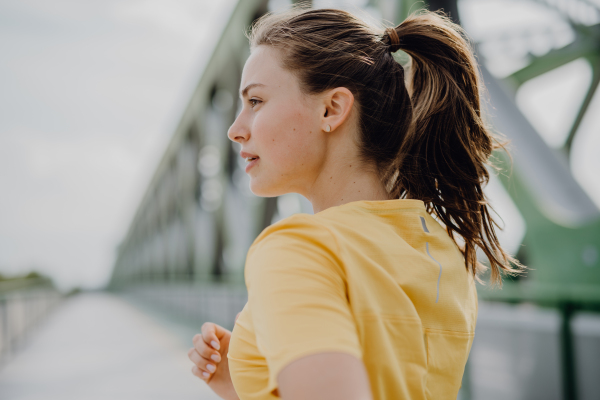 Young woman jogging at a city bridge, healthy lifestyle and sport concept.