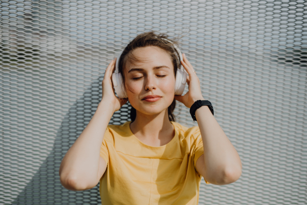 Portrait of young woman listening the music trough headphones.