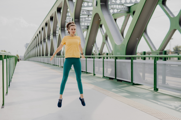 Young woman doing stretching in a city, preparing for run, healthy lifestyle and sport concept.