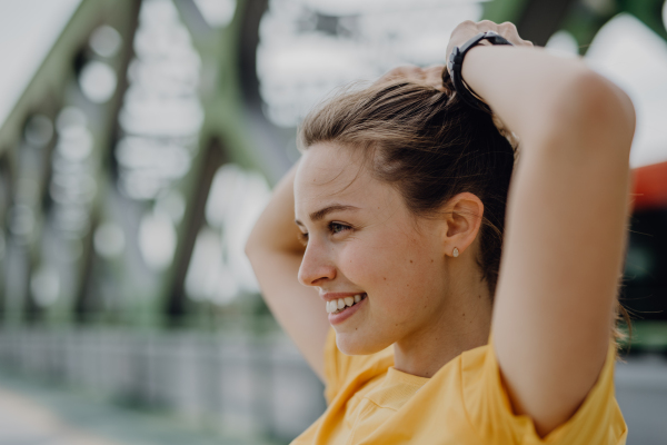 Side view of young woman preparing for run in city.