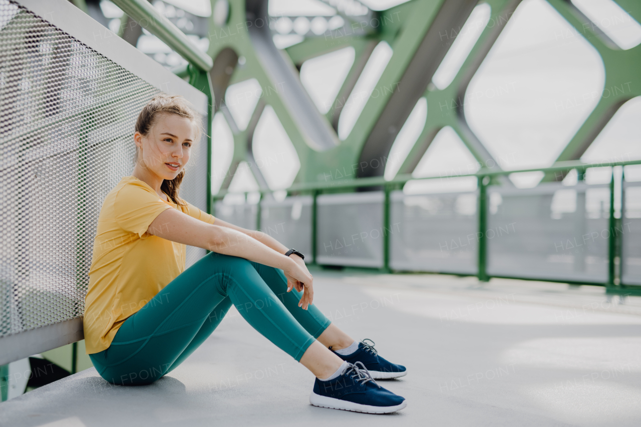 Portrait of young sportive woman resting outdoor in a city.