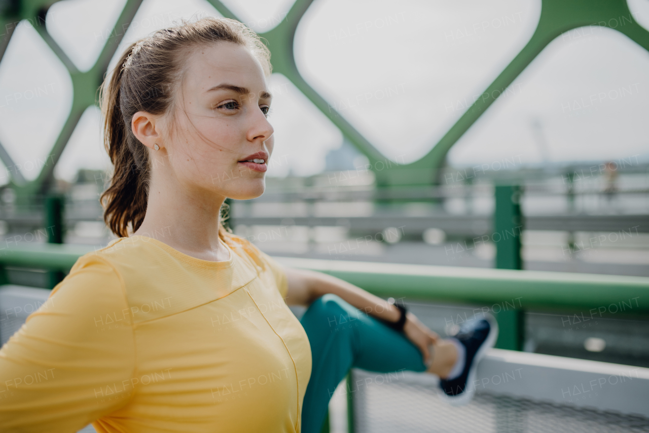 Young woman doing stretching in a city, preparing for run, healthy lifestyle and sport concept.