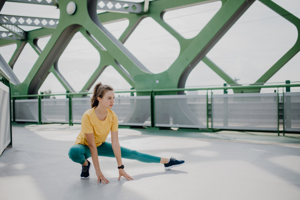 Young woman doing stretching in a city, preparing for run, healthy lifestyle and sport concept.