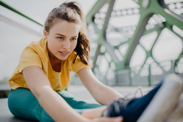 Young woman doing stretching in a city, preparing for run, healthy lifestyle and sport concept.