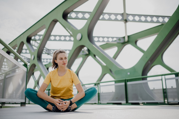 Portrait of young sportive woman resting outdoor in a city after running.