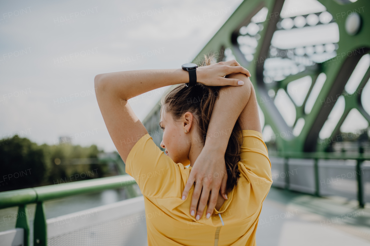 Young woman doing stretching in a city, preparing for run, healthy lifestyle and sport concept.