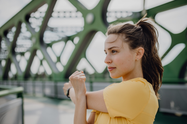 Young woman doing stretching in a city, preparing for run, healthy lifestyle and sport concept.