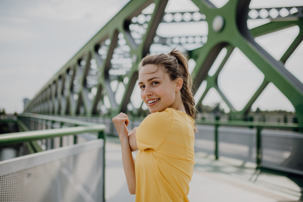 Young woman doing stretching in a city, preparing for run, healthy lifestyle and sport concept.