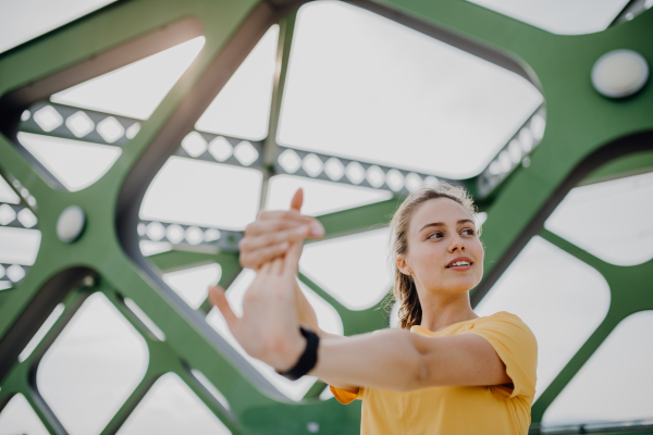 Young woman doing stretching in a city, preparing for run, healthy lifestyle and sport concept.