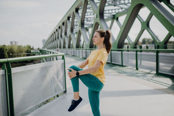 Young woman doing stretching in a city, preparing for run, healthy lifestyle and sport concept.