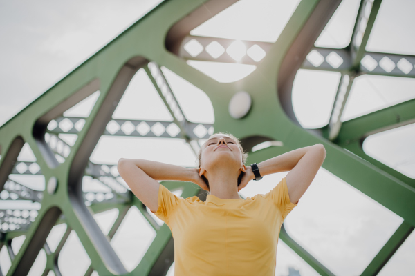 Young woman doing stretching in a city, preparing for run, healthy lifestyle and sport concept.