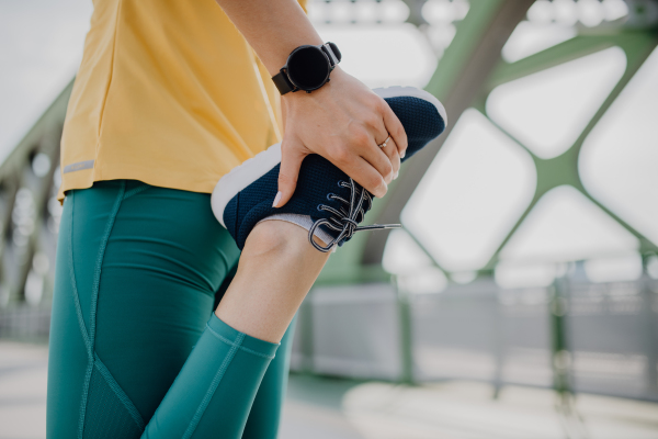 Close-up of woman doing stretching in a city, preparing for run, healthy lifestyle and sport concept.