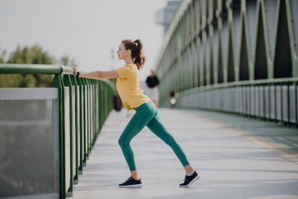 Young woman doing stretching in a city, preparing for run, healthy lifestyle and sport concept.