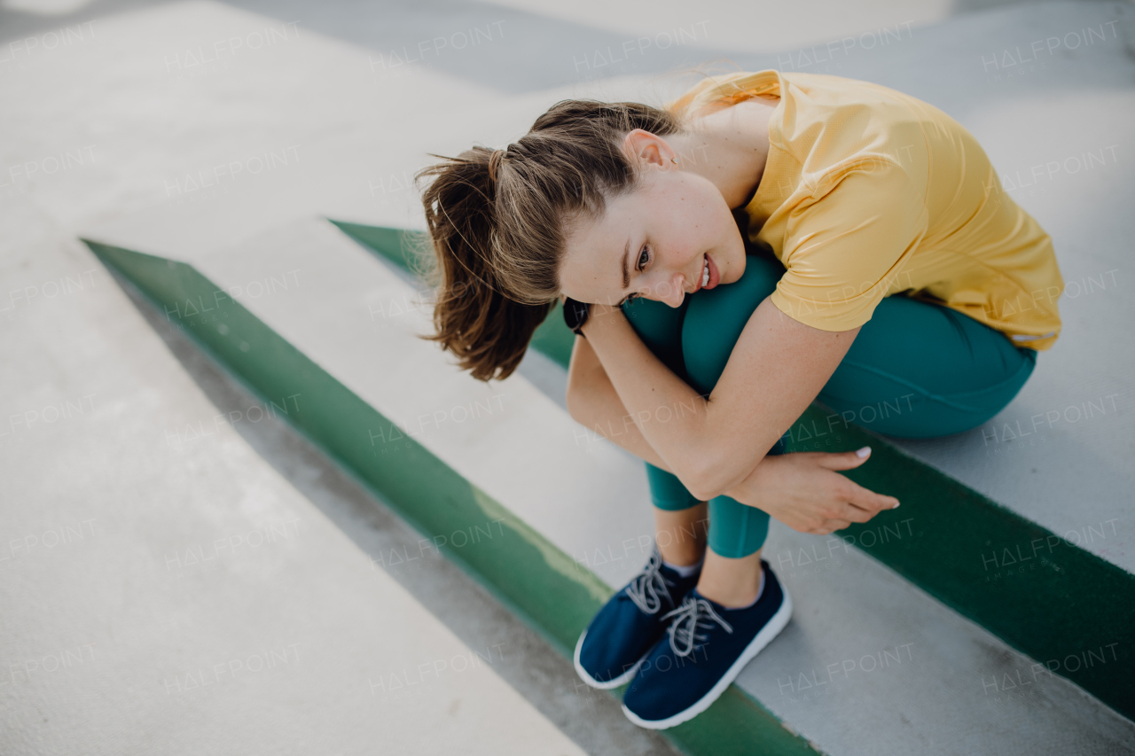 Portrait of young sportive woman resting outdoor in a city.