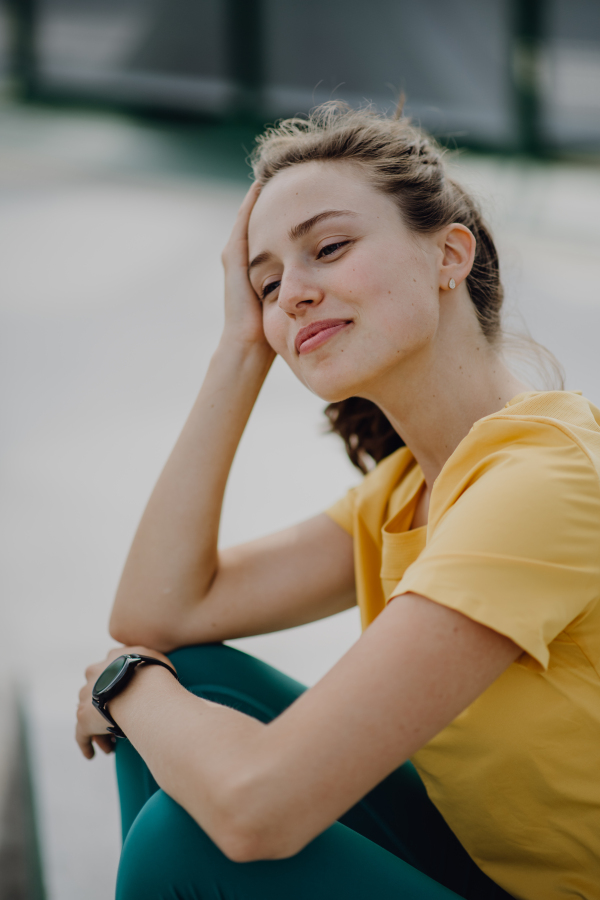 Portrait of young sportive woman resting outdoor in a city.