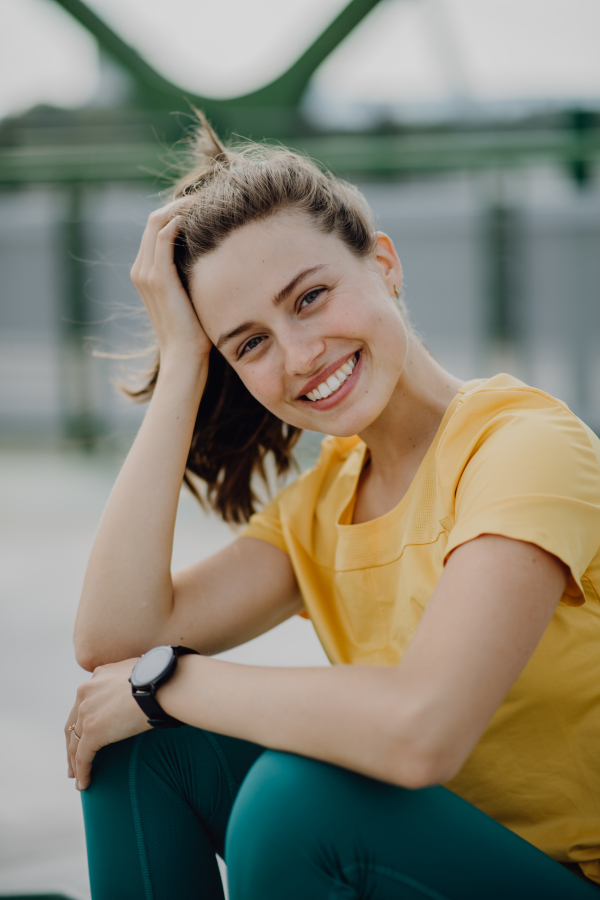 Portrait of young sportive woman resting outdoor in a city.