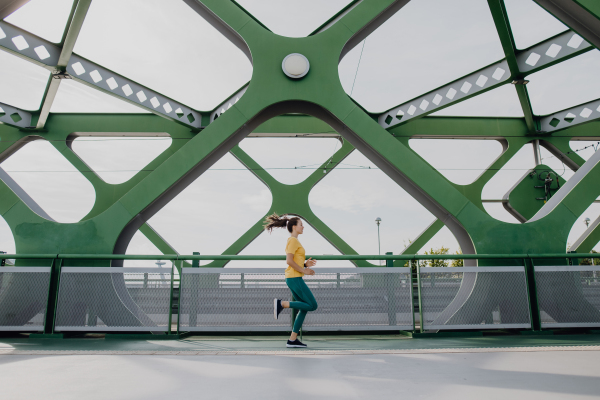 Young woman jogging at a city bridge, healthy lifestyle and sport concept.