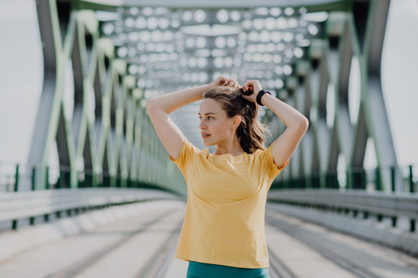 Portrait of young sportive woman resting after run outdoor in a city.