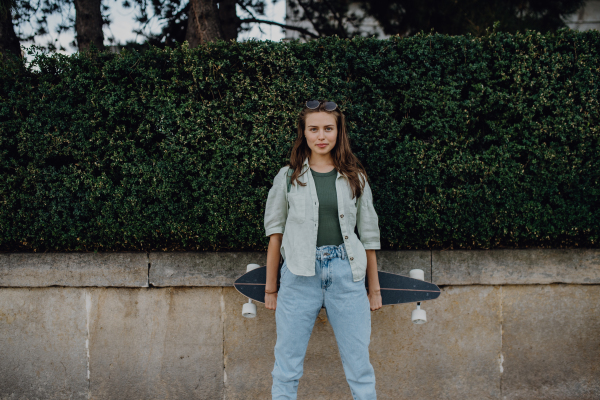 Portrait of young happy woman outdoor with a skateboard. Youth culture and commuting concept.