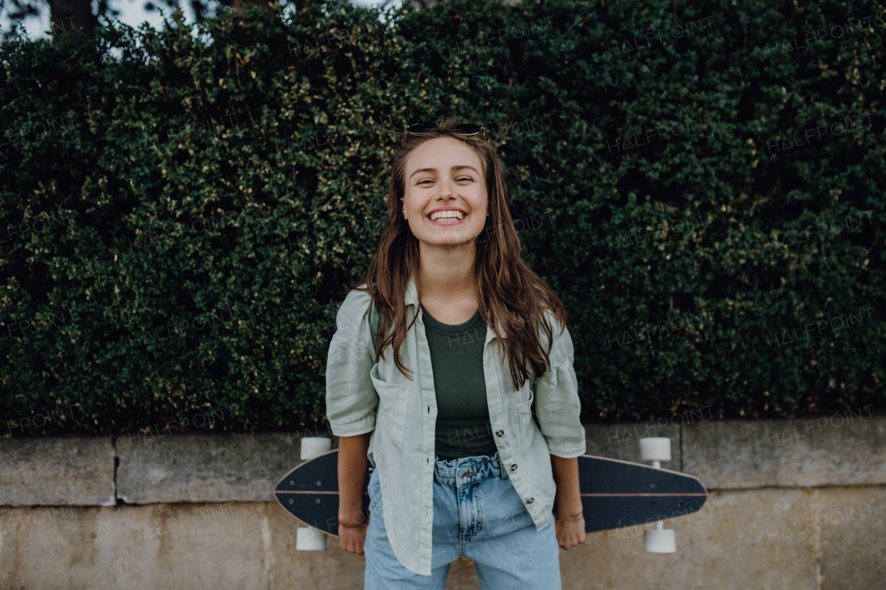 Portrait of young happy woman outdoor with a skateboard. Youth culture and commuting concept.