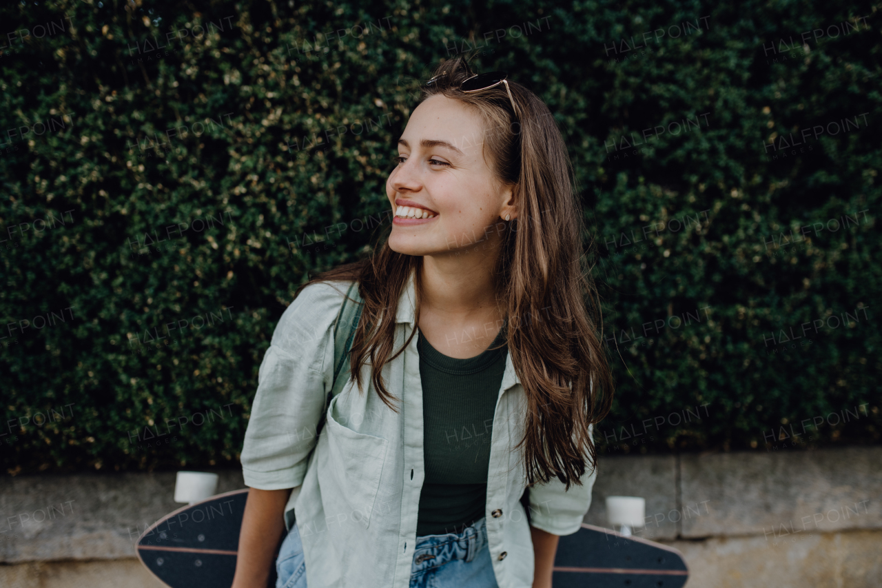 Portrait of young happy woman outdoor with a skateboard. Youth culture and commuting concept.