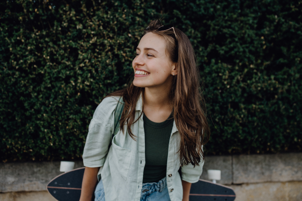 Portrait of young happy woman outdoor with a skateboard. Youth culture and commuting concept.