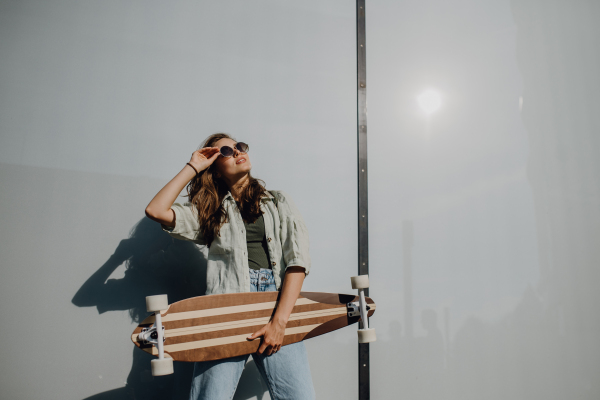 Portrait of young happy woman outdoor with a skateboard. Youth culture and commuting concept.