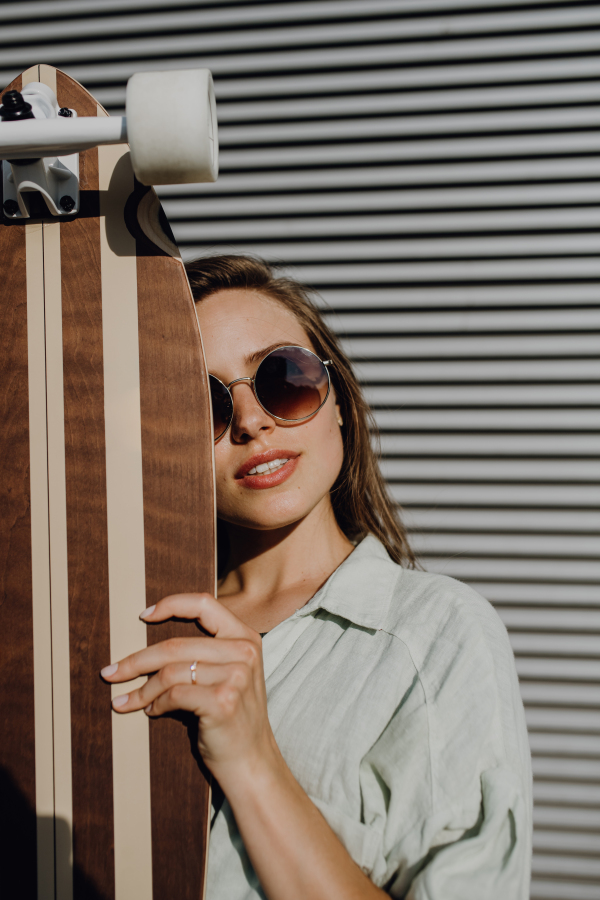 Portrait of young woman outdoor with a skateboard. Youth culture and commuting concept.