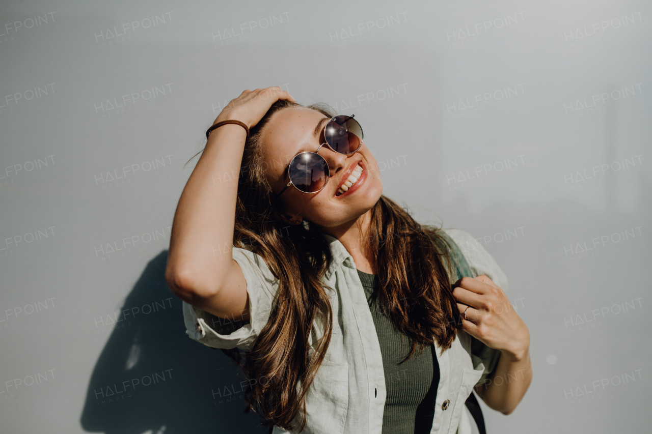 Portrait of happy young woman outdoor with a backpack and sunglasses.