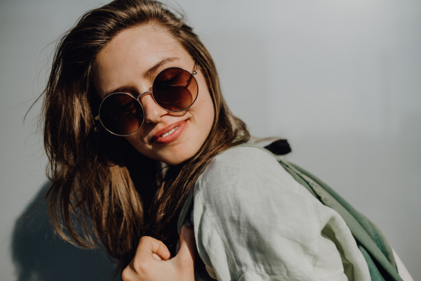 Portrait of happy young woman outdoor with a backpack and sunglasses.