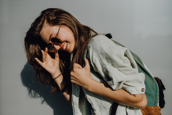 Portrait of happy young woman outdoor with a backpack and sunglasses.