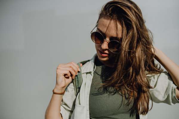 Portrait of happy young woman outdoor with a backpack and sunglasses.