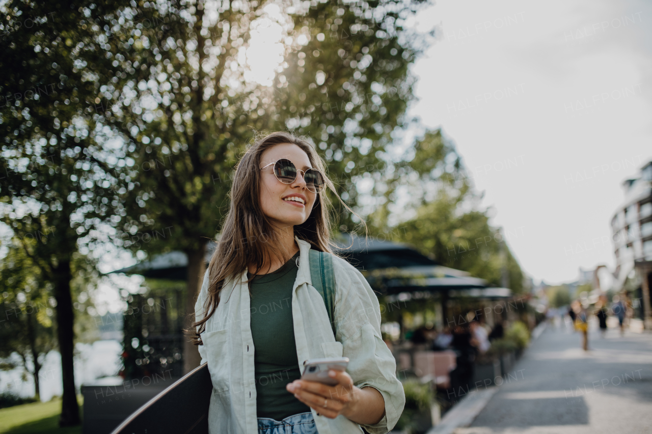 Portrait of young happy woman outdoor with a skateboard. Youth culture and commuting concept.