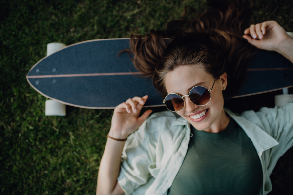 Top view of young woman lying on the grass with a skateboard.