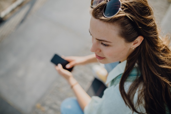 High angle view of young woman with smartphone outdoor in city.