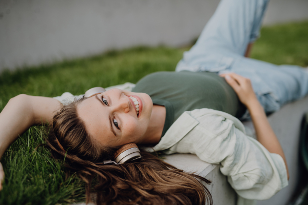 Young woman resting in a city, enjoying the music trough headphones.