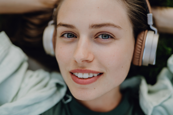 Portrait of young woman listening the music trough headphones.