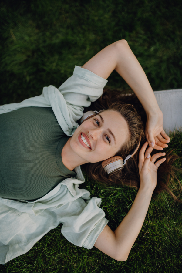 Young woman resting in a city, enjoying the music trough headphones.