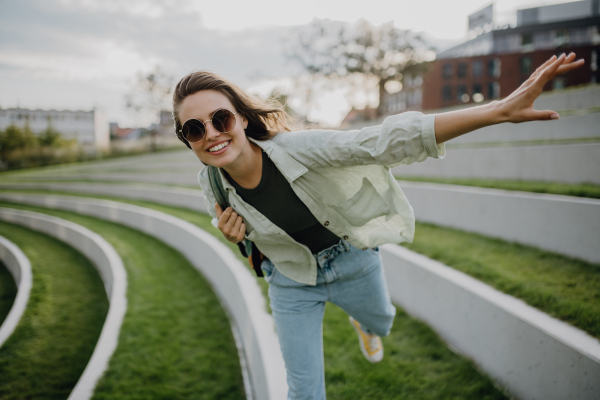 Happy young woman feeling free, posing during walking in a city.