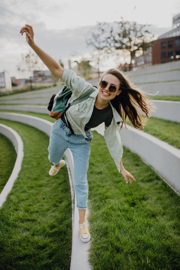 Happy young woman feeling free, posing during walking in a city.