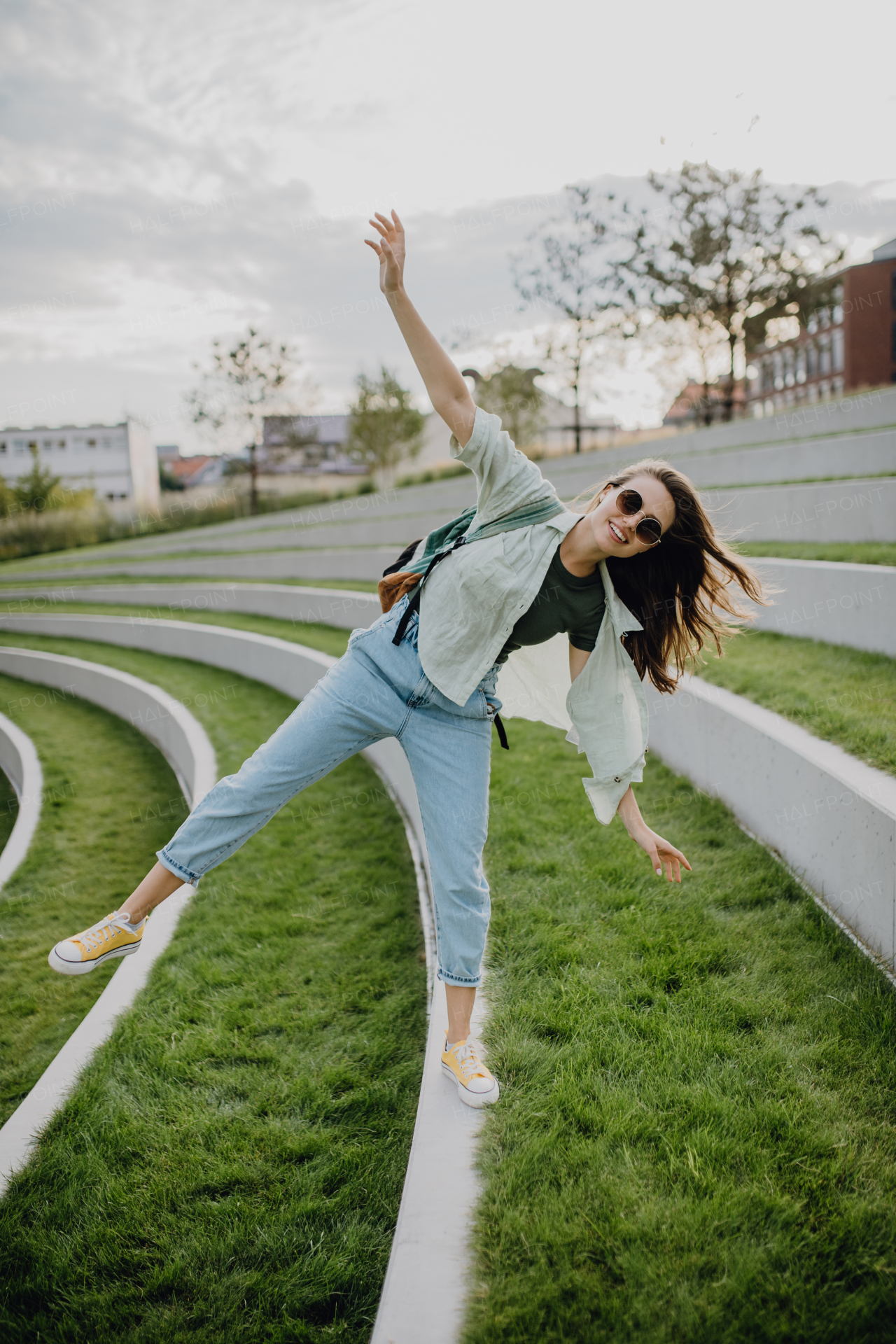 Happy young woman feeling free, posing during walking in a city.