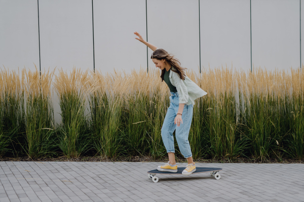 Young woman ridding a skateboard in a city. Youth culture and commuting concept.