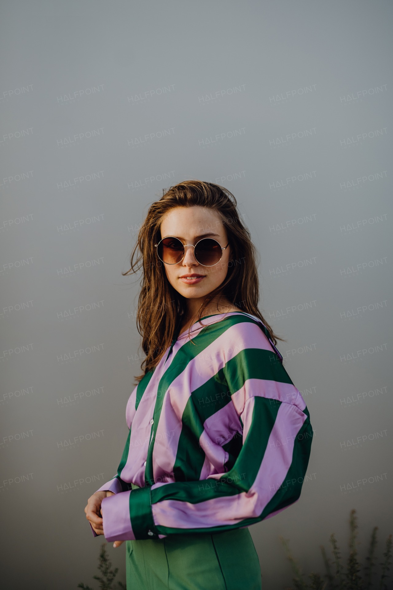 Portrait of beautiful young woman outdoor in a city, during sunset.