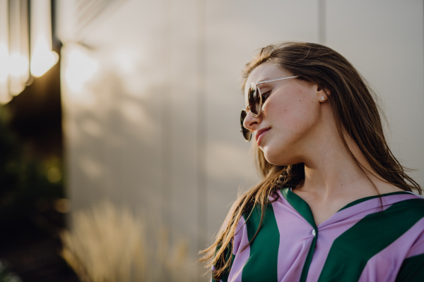 Portrait of beautiful young woman outdoor in a city, during sunset.