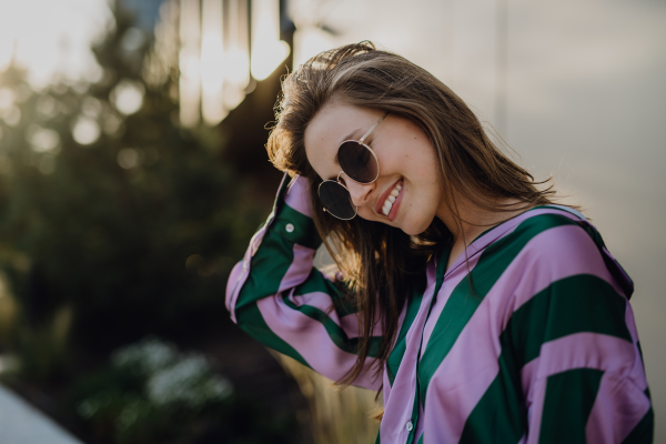 Portrait of beautiful young woman outdoor in a city, during sunset.