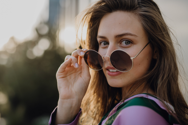 Portrait of beautiful young woman outdoor in a city, during sunset.