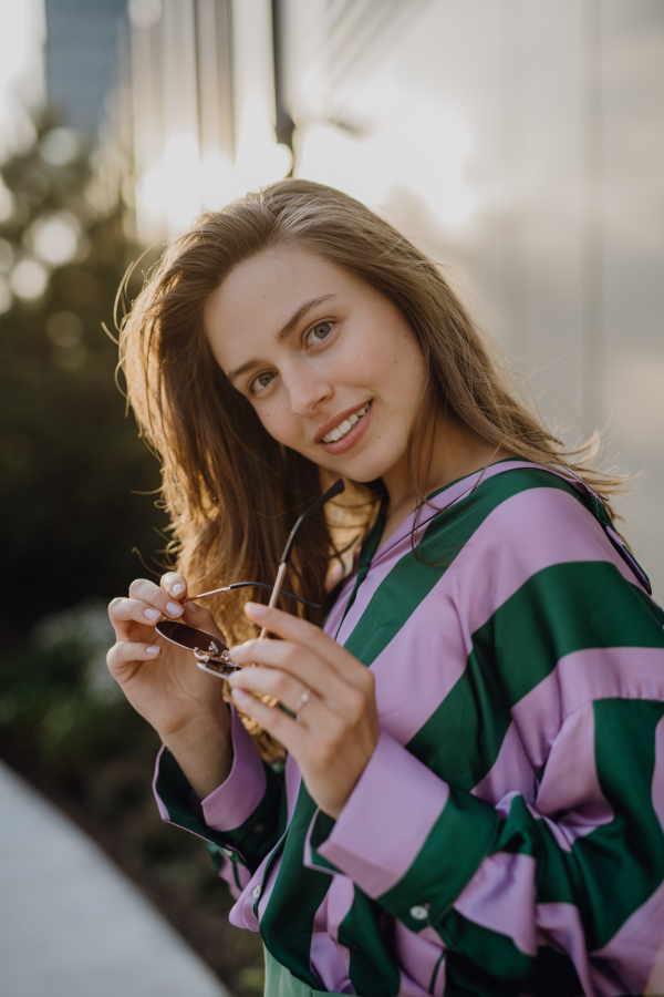 Portrait of beautiful young woman outdoor in a city, during sunset.