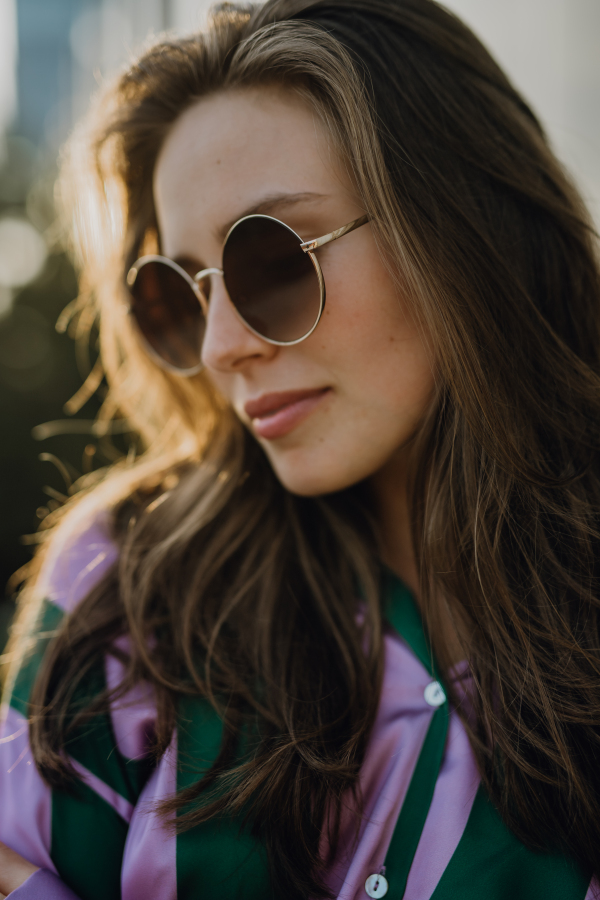 Portrait of beautiful young woman outdoor in a city, during sunset.