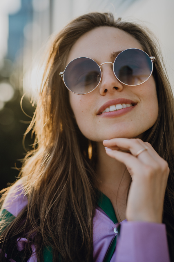 Portrait of beautiful young woman outdoor in a city, during sunset.