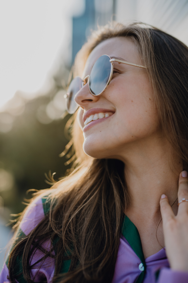 Portrait of beautiful young woman outdoor in a city, during sunset.